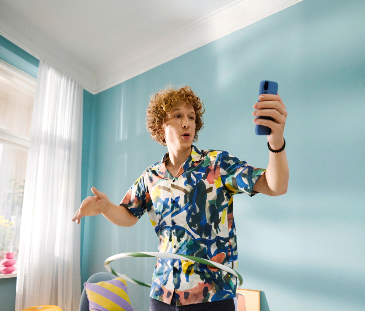 Mann mit buntem Hemd hoolert und schaut ins Handy